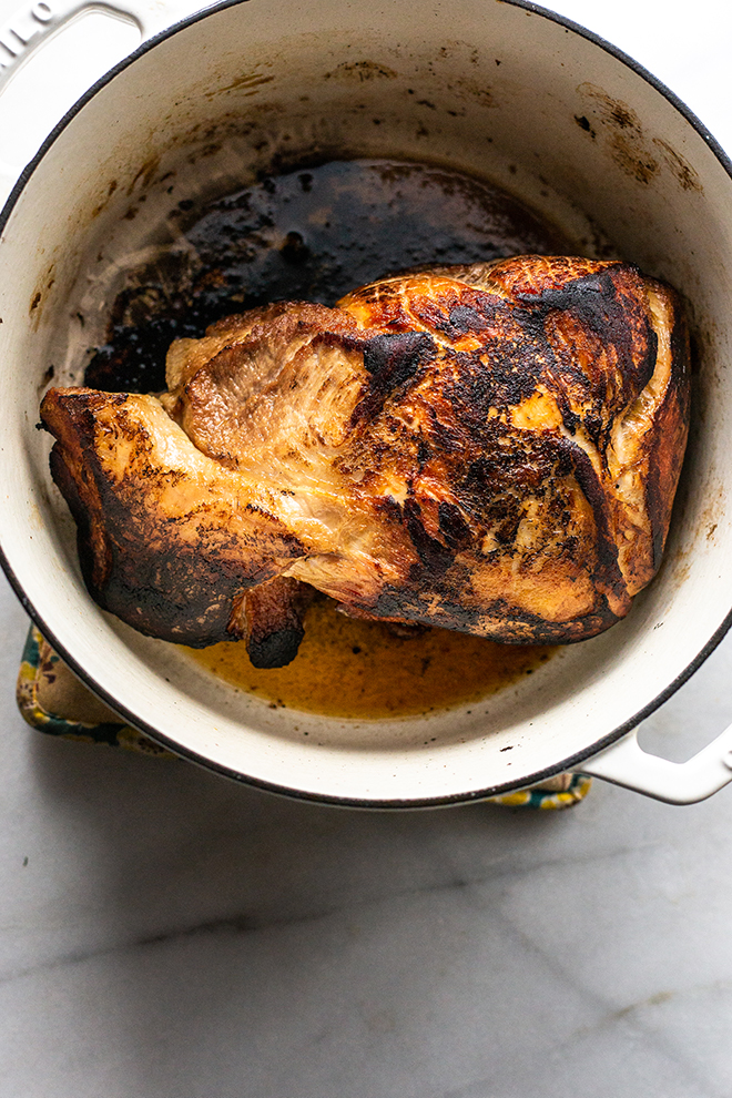 seared pork shoulder in a white dutch oven 