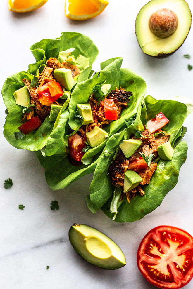 tacos in lettuce wraps with avocado and tomato on a white background 
