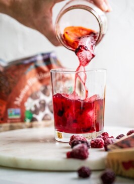 pouring a Blackberry Raspberry Old Fashioned from a jar into a glass