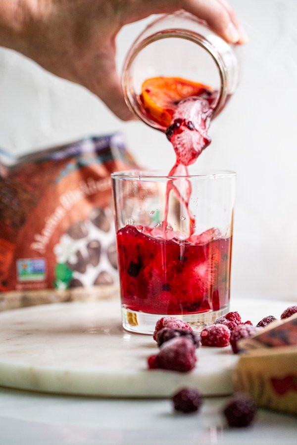 pouring a Blackberry Raspberry Old Fashioned from a jar into a glass