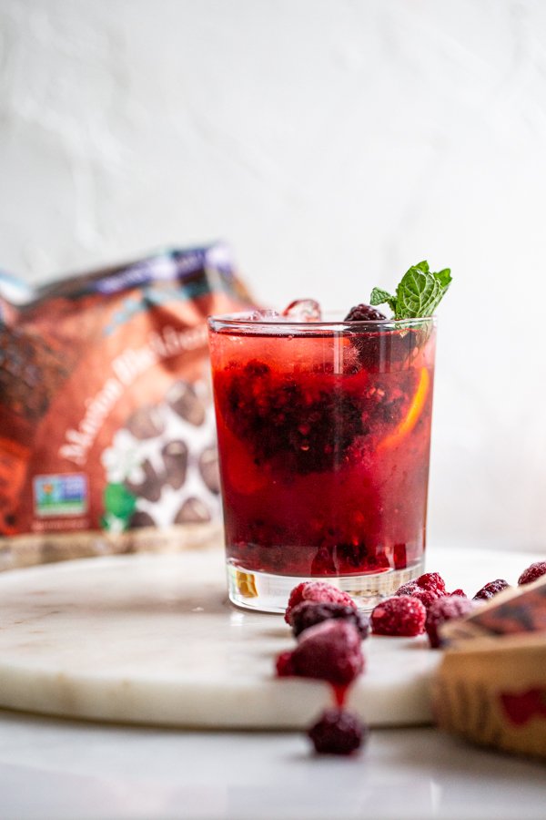 Blackberry Raspberry Old Fashioned Cocktail in a glass with mint on a white counter