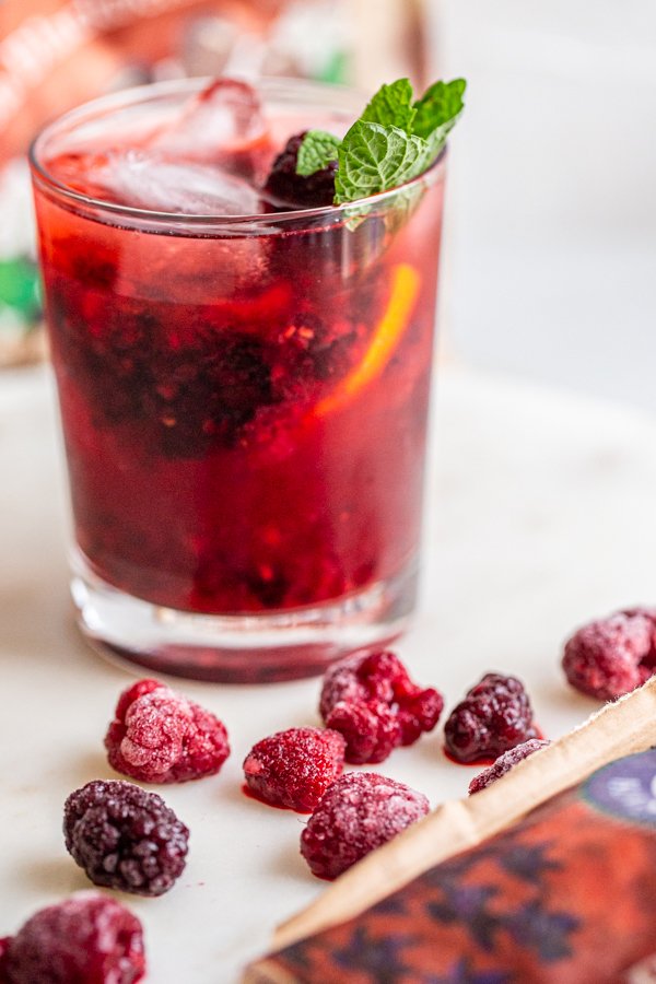 Blackberry Raspberry Old Fashioned Cocktail in a glass with mint on a white counter