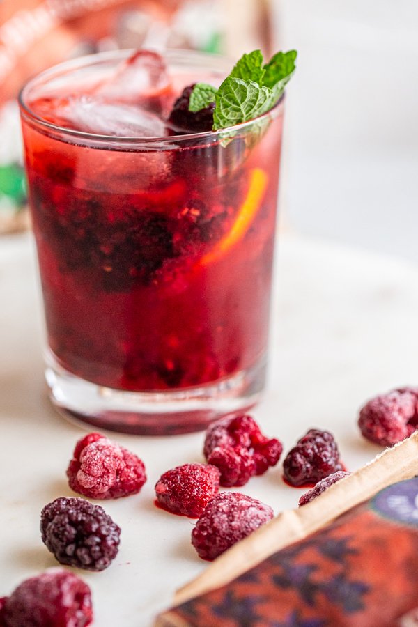 Blackberry Raspberry Old Fashioned Cocktail in a glass with mint on a white counter