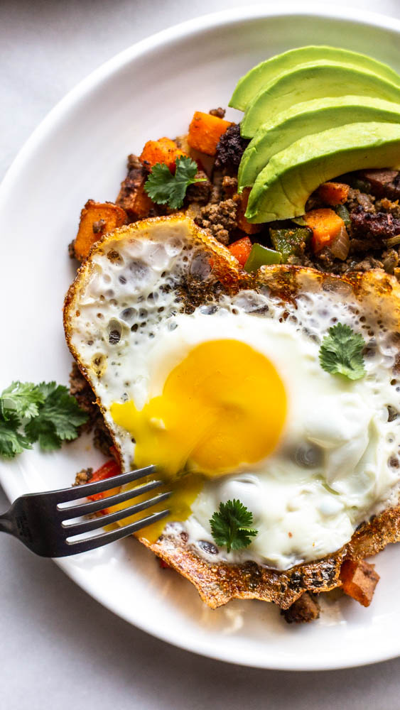 Looking for a better for you hash for breakfast (or whenever)? This Whole30 Bison Sweet Potato Hash has crispy sweet potatoes and veggies, lean bison and the perfect blend of spices. You can top with fried eggs, avocado, and cilantro for the best brunch or breakfast. This lower carb version can be made with turkey, beef, or venison, too. You make it on the stovetop and crisp it in the oven for the perfect potato. This recipe is #whole30approved and #paleo. #healthy #healthyrecipe #paleofood #breakfast 