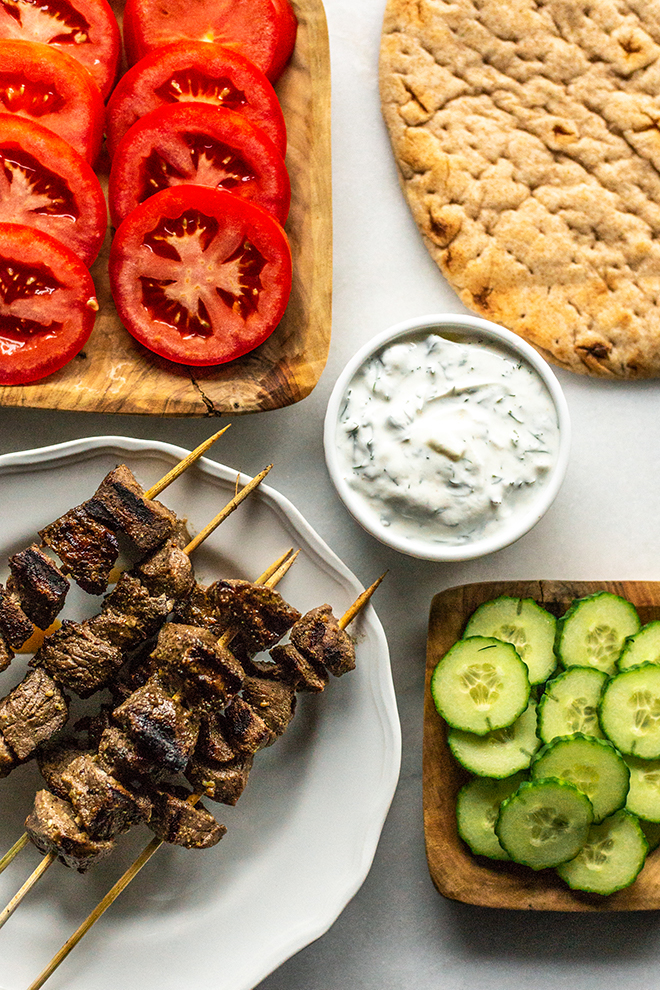 tomatoes, flatbread, tzatziki sauce, cucumber and grilled venison on a white background 