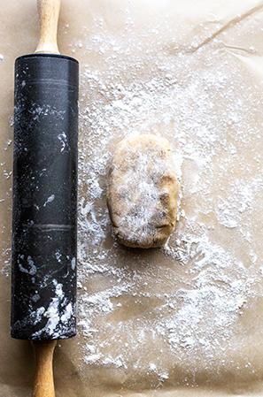 pie crust with a rolling pin on brown parchment with flour 