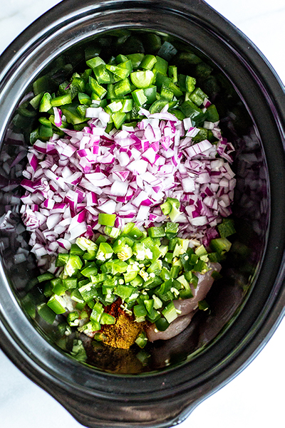 bell peppers and red onions chopped in a black slow cooker 