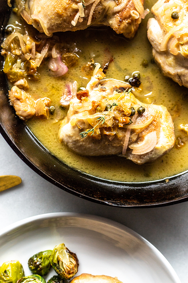 chicken thighs in golden sauce in a skillet 