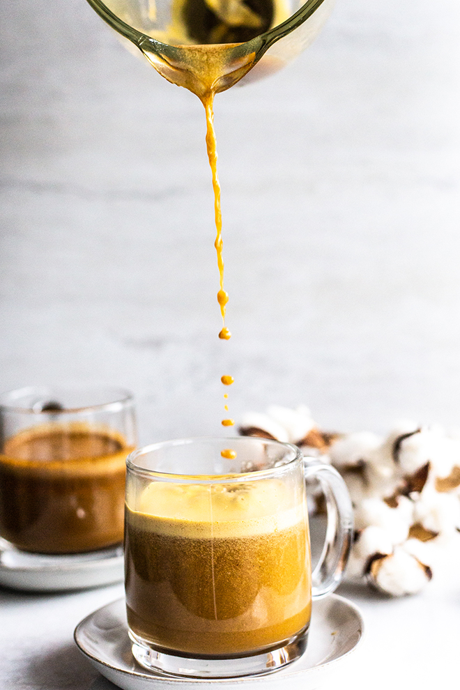 pouring a pumpkin chai latte in a glass mug 