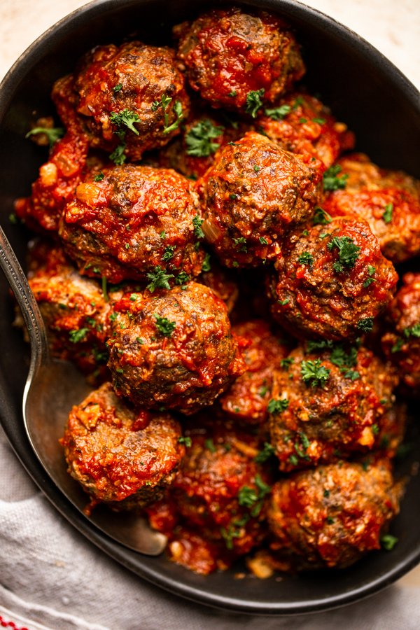 venison meatballs in a black bowl with red sauce