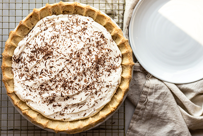 Whipped cream on a pie on a gold cooling rack with chocolate shavings 