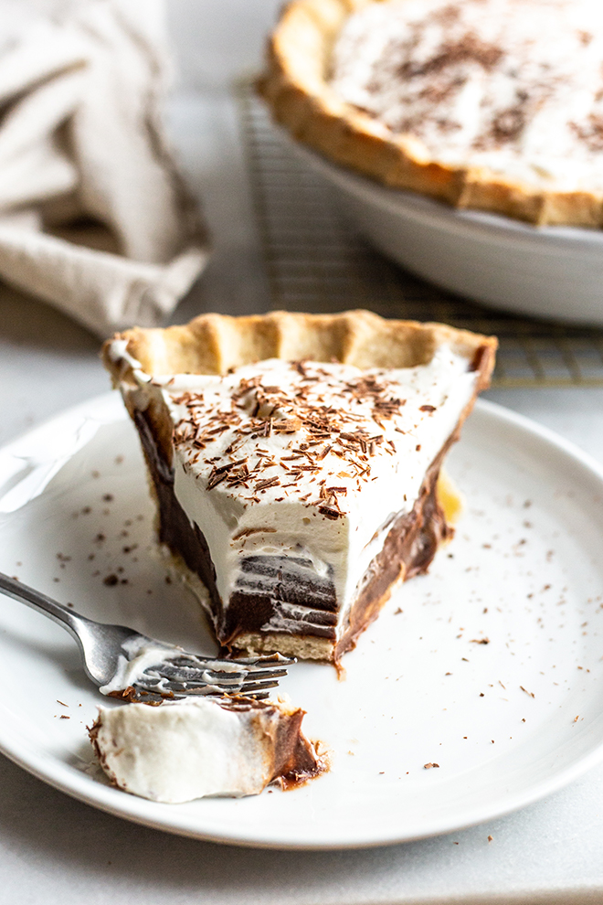 chocolate silk pie with whipped cream topping with a bite out of it 