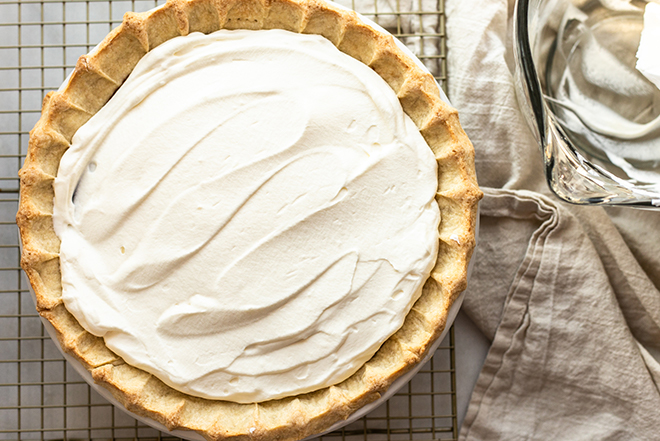 Whipped cream on a pie on a gold cooling rack