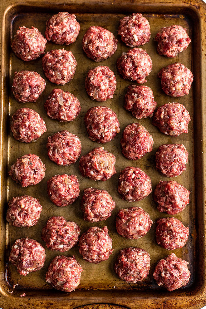 meatballs rolled on a gold baking sheet