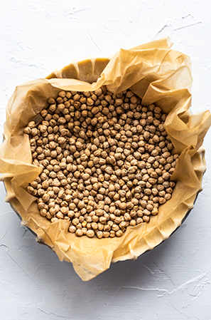 pie crust weighed down with chickpeas in parchment on a white background 