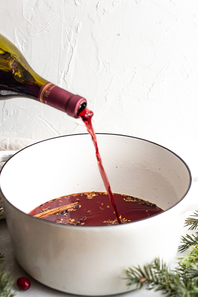 red wine pouring into a white pot with a white background 