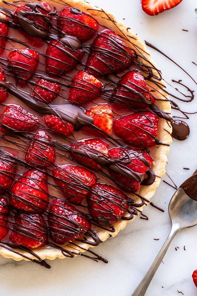 Fresh strawberries with hints of orange and vanilla fill a flakey tart crust and everything is covered in a chocolate drizzle.