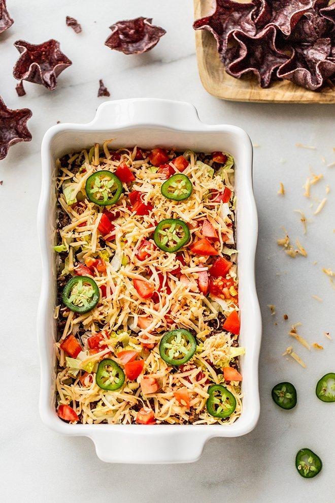 Easy venison taco dip is layers of Greek yogurt cream, chili lime spiced ground venison with Pepper Jack cheese and fresh veggies.