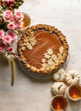 pumpkin pie on a cream board with pretty crust and pink flowers