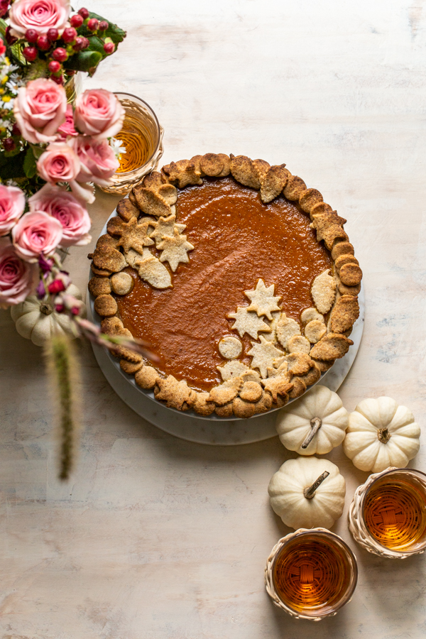 pumpkin pie on a cream board with pretty crust and pink flowers