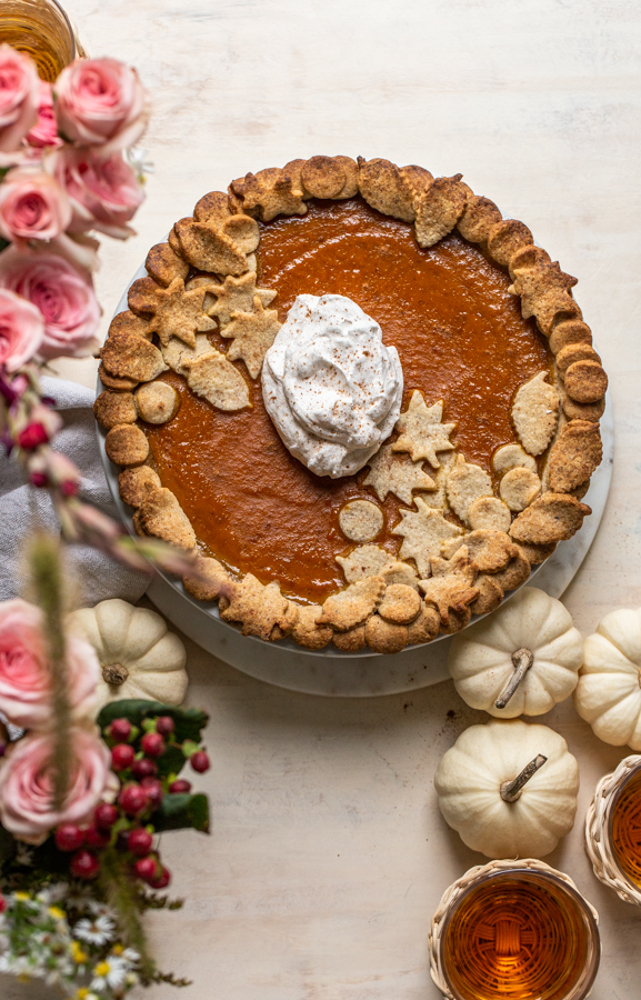 maple bourbon pumpkin pie with pink flowers and whipped cream