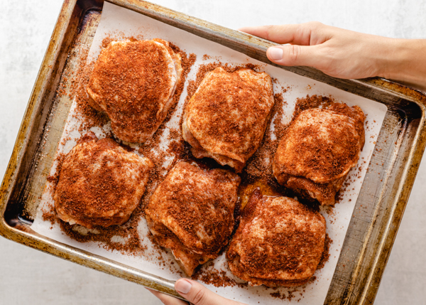 bone in skin on chicken thighs on a baking sheet, unbaked