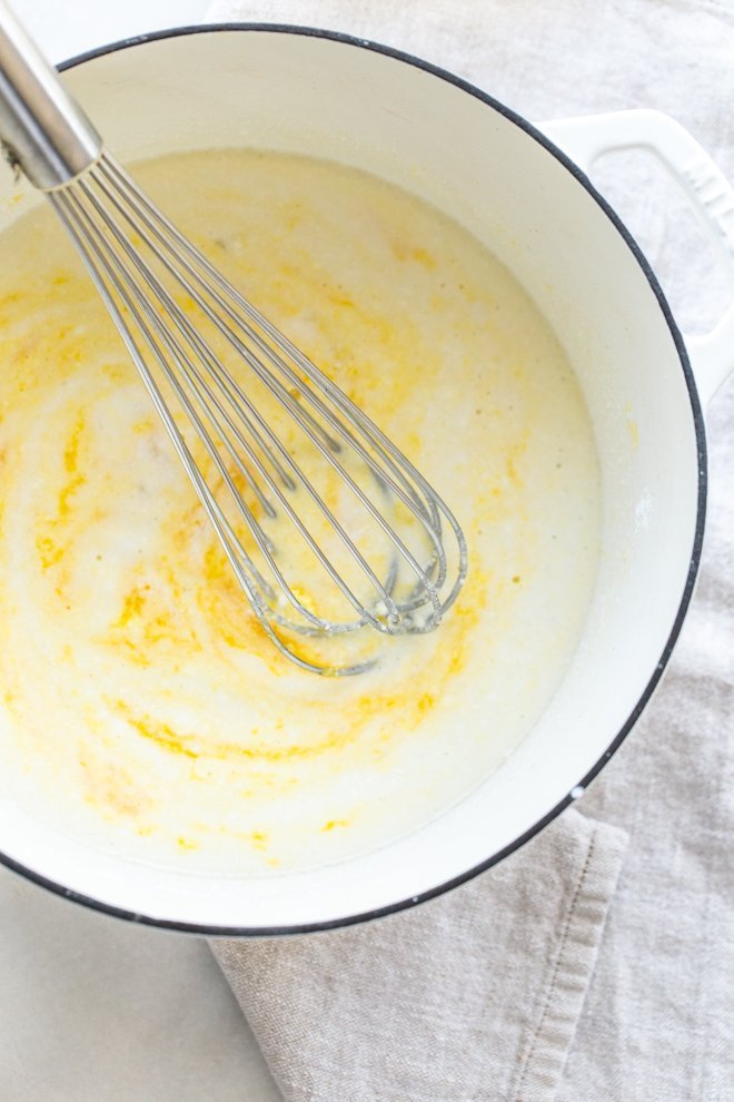 coconut milk, egg yolks and sugar in a white dutch oven pot with a whisk