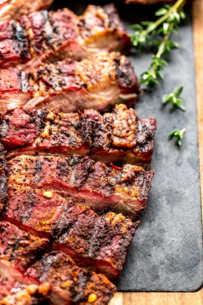 venison brisket on a wood cutting board with slate and thyme