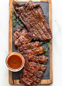 venison brisket with barbecue sauce on a wood cutting board with slate