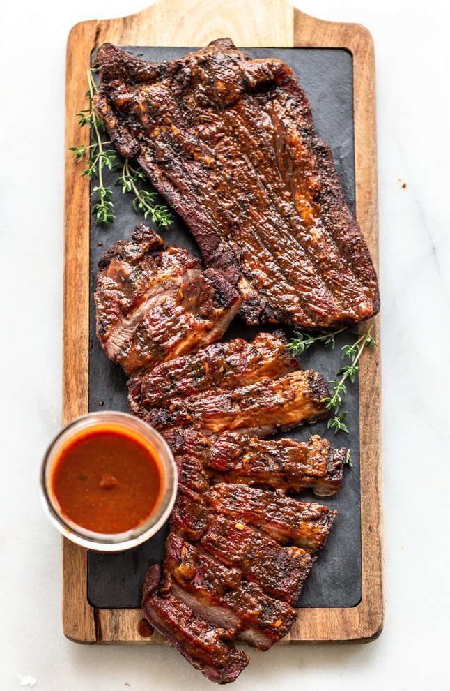 venison brisket with barbecue sauce on a wood cutting board with slate 