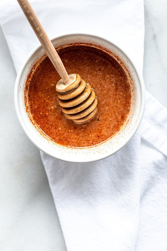 honey with cayenne in a white bowl with a wooden stirrer and a white napkin 