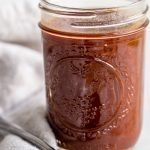 paleo BBQ sauce in a glass jar with a cream linen on a white background
