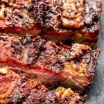 venison brisket with barbecue sauce on a wood cutting board with slate