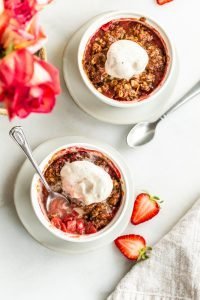 Gluten Free Strawberry Crisp for Two on a white background with strawberries on a white background with vanilla ice cream shot overhead