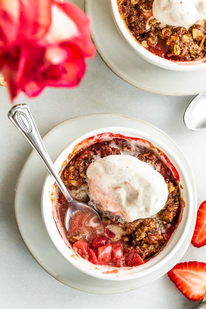 Gluten Free Strawberry Crisp for Two on a white background with strawberries on a white background with vanilla ice cream