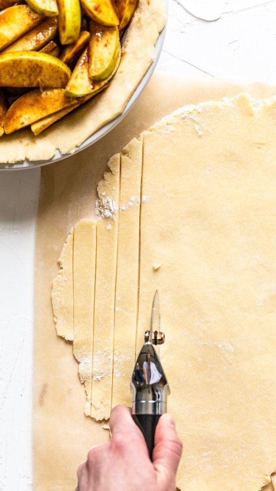 lattice being cut with a pizza cutter out of pie dough