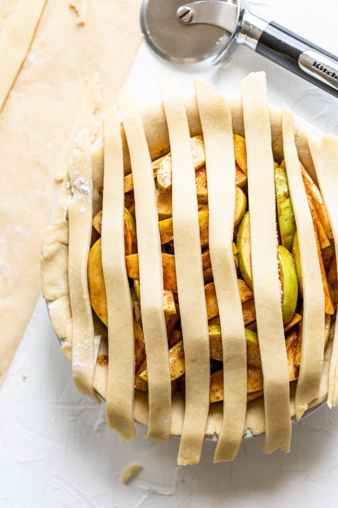 a lattice apple pie being made on a white background, unbaked