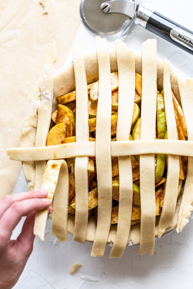 a lattice apple pie being made on a white background, unbaked