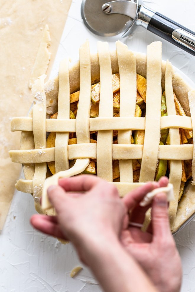 a lattice apple pie being made on a white background, unbaked