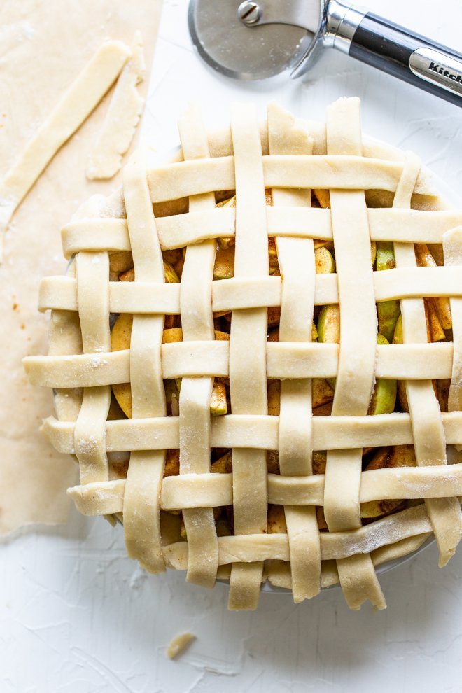 a lattice apple pie being made on a white background, unbaked