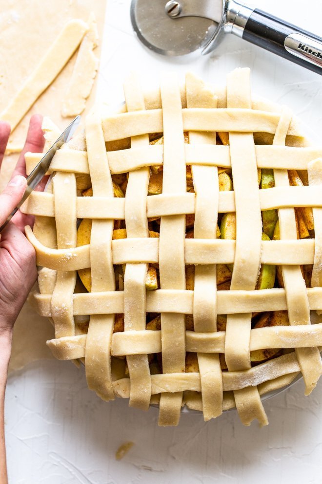 a lattice apple pie being made on a white background, unbaked