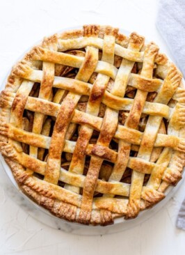 a classic lattice apple pie on a white background with a grey linen