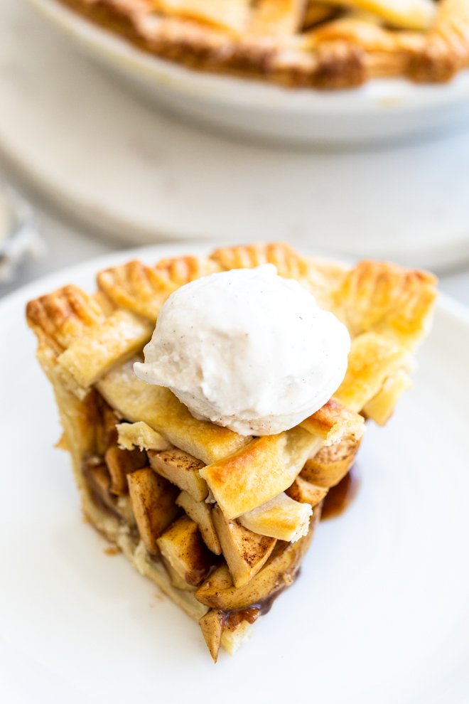 a slice of apple pie with ice cream on a white plate