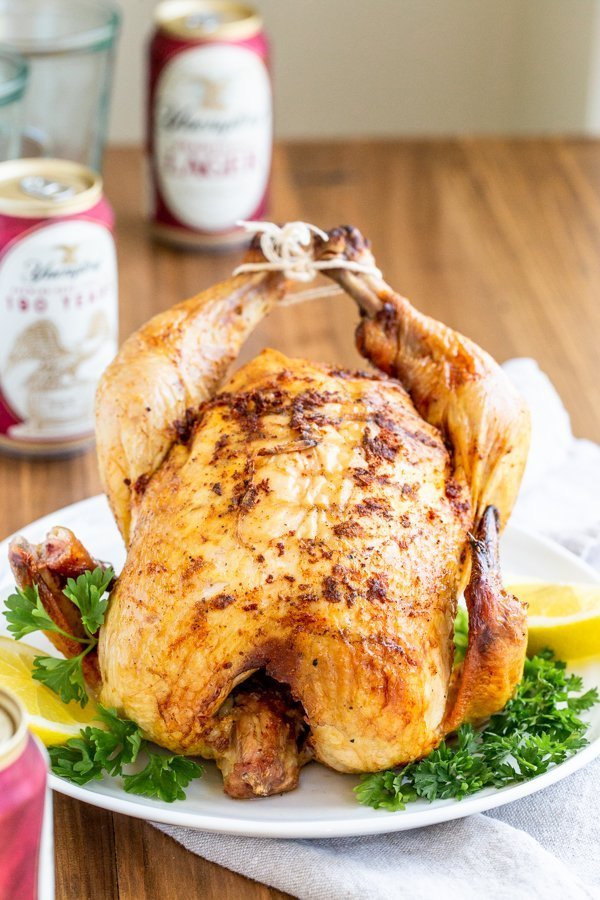 beer can chicken on a white platter on a wood table