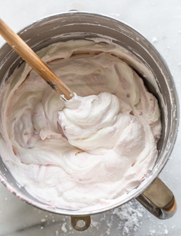 whipped cream in a metal bowl with a spatula folding in