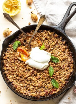 peach crisp with spoons eating the crisp on a white background
