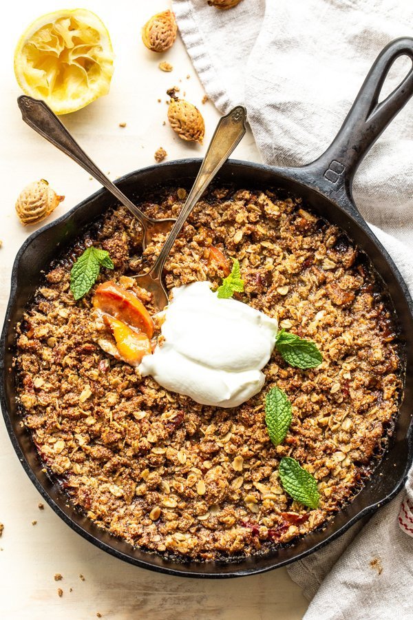 peach crisp with spoons eating the crisp on a white background