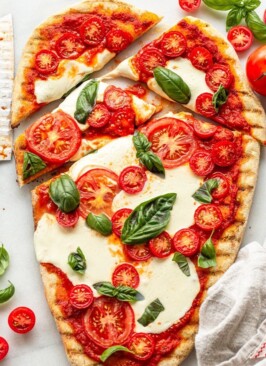 Traeger grilled pizza recipe cut on a marble slab with fresh basil