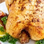 beer can chicken on a white platter with garnish