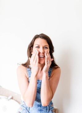 girl with brunette hair in overalls applying a face mask